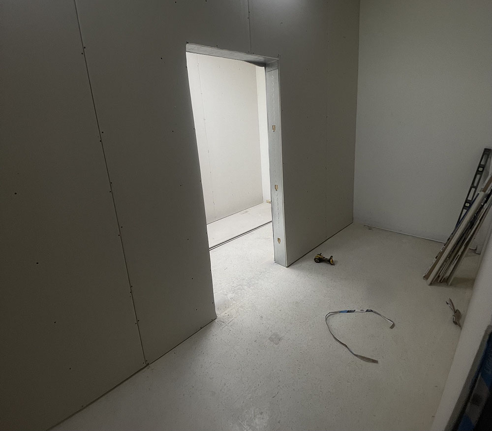 Drywall boards hung flush around commercial door opening